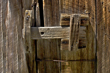 Old weathered wood sliding latch with bailing wire repair
