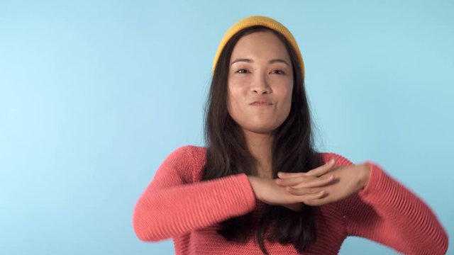 Cute and funny looking young asian model dancing. Blue background.