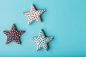 Close-up of three homemade glazed gingerbread cookies made in the form of stars on a blue background. Handmade cookies. Free space.