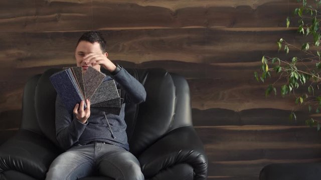 the man chooses the color of the new carpet according to the pattern book in the flooring shop