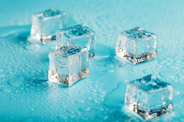 Ice cubes are scattered with water drops scattered on a blue background. Close up.