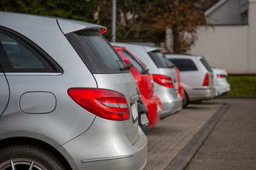 back sides of cars in silver and red on a parking lot - front focus with blurry background