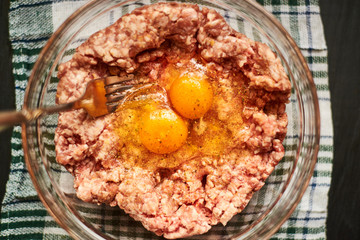 Minced meat with raw egg in a plate. Cooking meat products.