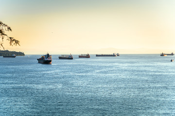 Obraz premium Cargo ships anchored in a bay at sunset. English bay, Vancouver, BC, Canada.