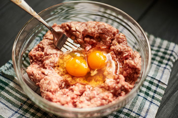 Minced meat with raw egg in a plate. Cooking meat products.