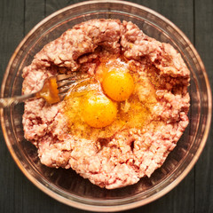 Minced meat with raw egg in a plate. Cooking meat products.