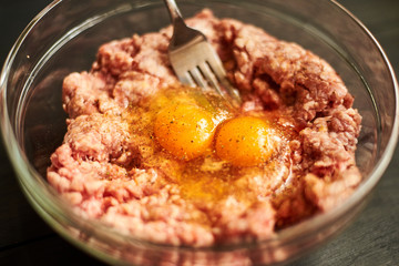 Minced meat with raw egg in a plate. Cooking meat products.