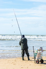 Saint Hillaire de Riez, France-February 23, 2020: view of an old fisherman with his fishing rod in his hand, he launches his bait to the ocean.