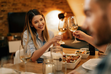 Happy woman toasting with friends during dinner at dining table.