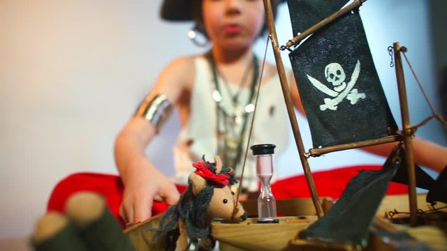 Close-up of a pirate kit in the hands of a child. A boy in a pirate costume imitates a pirate battle and moves a ship with his hands. Stress relief in self-isolation COVID-19.