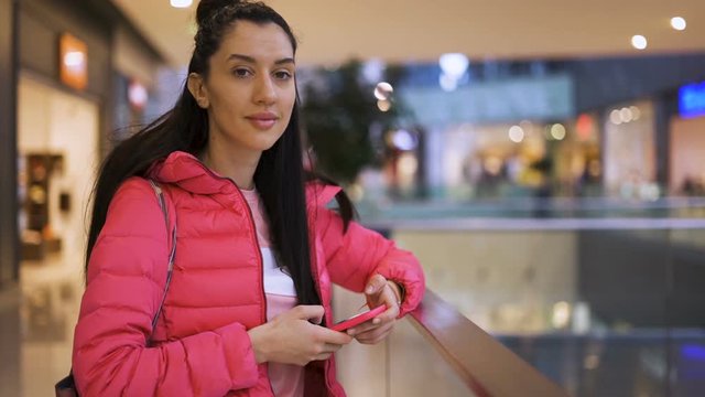 Close view of smiling girl using phone waiting in the mall