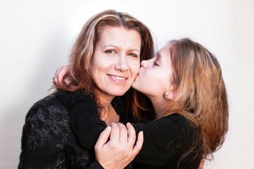 A teenage girl sincerely hugs her mom and kisses her, congratulates her on mother's day. The woman...