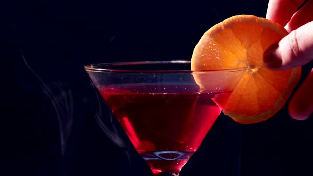 Fancy drink in close up! Smoke in the background. An orange is putted on the glass.