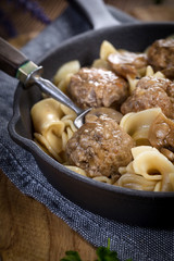 Pork meatballs with noodles in a cast iron skillet.