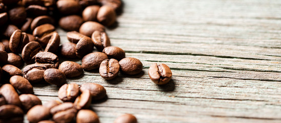 Roasted coffee beans on a wooden background, close-up, copy space.