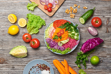 Rainbow salad with tomato, lettuce, cucumber, red cabbage, carrot, radish. Paleo diet, healthy vegan and balanced food concept. Fresh mix green Buddha bowl homemade salad on wood, flat lay