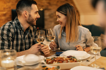 Happy couple toasting while having dinner at dining table.