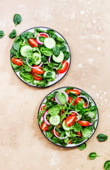 Spring vegan salad with spinach, cherry tomatoes, corn salad, baby spinach and red onion. Healthy food concept. Beige stone table.Top view. Copy space