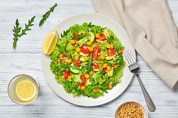Vegan greens salad, chickpeas, lettuce, arugula, cherry tomatoes. Home made vegetarian green salad. Diet, vitamin food concept on wood. Tasty veg mix leaves salad in bowl. Top view.