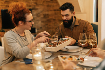 Young smiling couple having dinner at dining table.