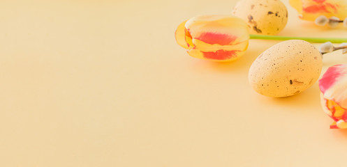 Easter composition with yellow tulips and eggs on a yellow background