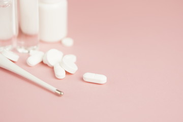 White medical pills and medical preparations in with bottles, glass ampoues, pink background. Closeup photo of medical preparations with copy spaes.