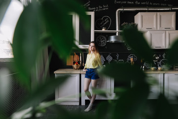 A girl drinking coffee in the kitchen at home. Young woman holding cup of coffee.  Girl drinking beverage in cafe. Good morning. 