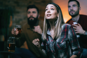 Young woman cheering while watching sports championship with her friends.