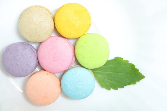 Closeup top view of colorful macaron stack like flower on white dish background. Flat lay style.