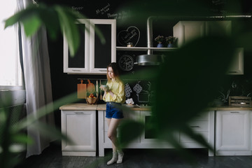 A girl drinking coffee in the kitchen at home. Young woman holding cup of coffee.  Girl drinking beverage in cafe. Good morning. 