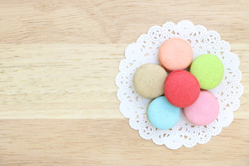 Closeup top view of colorful macarons stack like flower on wood background have copy space. Flat lay style.