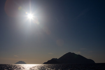 silhouette of Alicudi and Filicudi with sun rays and flare effect, Aeolian Islands, Messina, Sicily, Italy