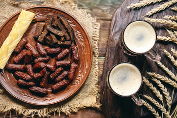 Frothy beer in the mug and plate with a snack top view background.