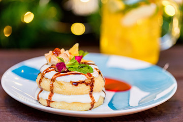 Cottage cheese pancakes or syrniki with cream, fruit jam and flower decoration