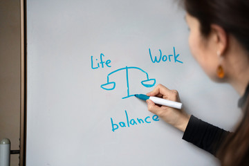 The girl draw  picture "life and work balance" on white board 