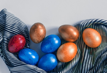 Colorful Easter eggs and silk textile material. Festive Easter holiday concept. View from above. Copy space. Top view