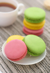 Fototapeta na wymiar Colorful macarons on white plate and cup of tea