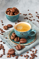 Coffee-shaped  cookies with cup of coffee on gray background