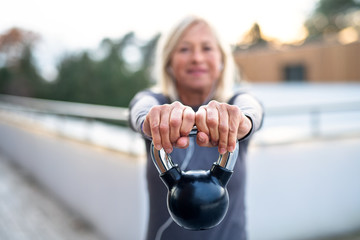 A senior woman with kettlebell outdoors doing exercise.