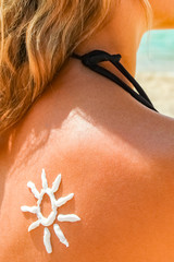 happy girl on the sea with a picture of the sun on her back