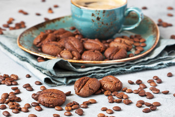 Coffee-shaped  cookies with cup of coffee on gray background