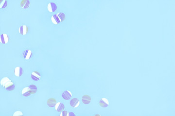 Pearl confetti on blue background. Flat lay, top view.