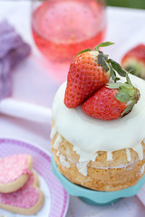 Small picnic with strawberry sponge cake and red drink on wooden table in garden