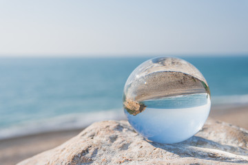 Fototapeta na wymiar Reflejos de una esfera de cristal de una playa pequeña