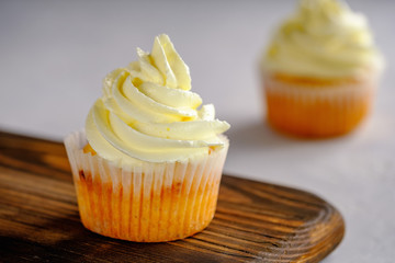 Delicate and delicious lemon cupcakes with cream on a wooden board