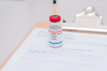 measles mumps and rubella vaccination concept with syringe in vaccine vial and clipboard with...