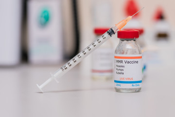 measles mumps and rubella vaccination concept with syringe in vaccine vial and other vials in background - obrazy, fototapety, plakaty