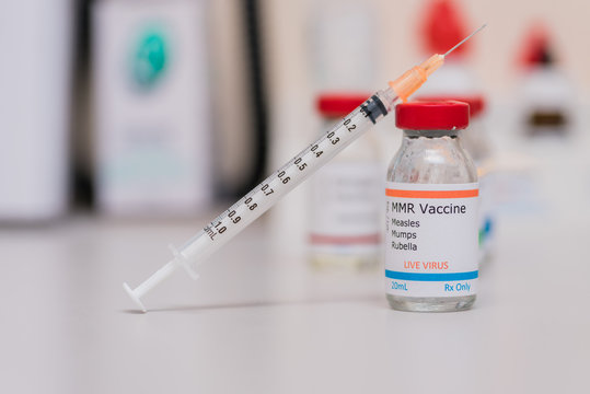 measles mumps and rubella vaccination concept with syringe in vaccine vial and other vials in background