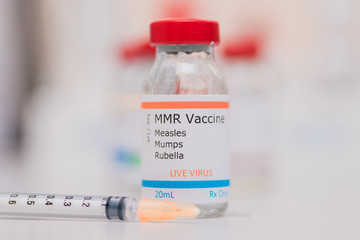 Measles, Mumps, and Rubella Vaccine Concept MMR Vaccination vial on counter with syringe in background