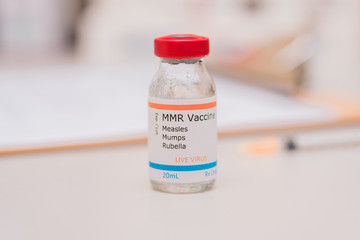 Measles mumps and rubella vaccine concept vial with patient chart and injection syringe in...